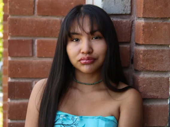 A headshot image of student staff Kelly Haven with a brick building in the background