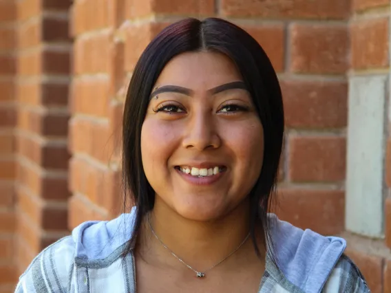 A headshot image of graduate assistant Olene Smith with a brick building in the background