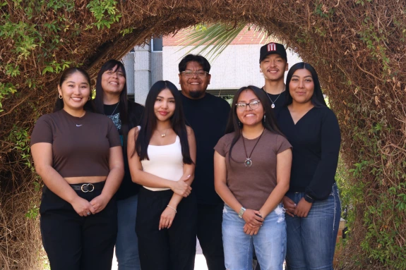 Group photo of Native American Student Affairs staff all standing in front of a grass covered building.