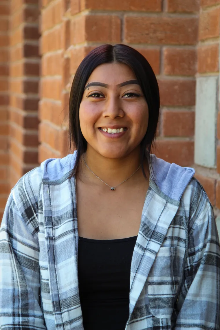 A headshot image of graduate assistant Olene Smith with a brick building in the background