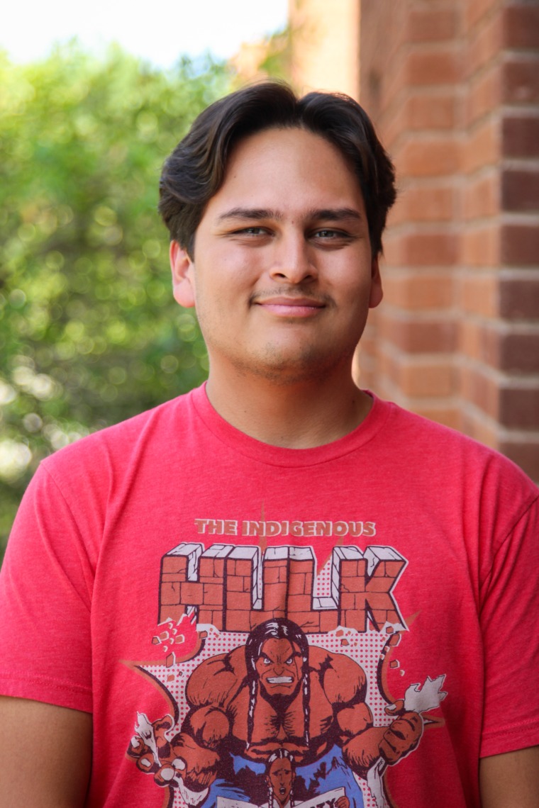 A headshot image of student staff Eric Trujillo with a brick building in the background